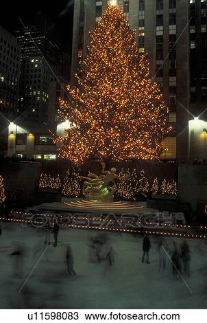 Stock Image -  New York City, NY, New York, downtown, Rockefeller Plaza, Christmas Tree, lights, evening, ice skating rink. Fotosearch