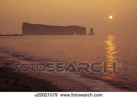 Stock Photo -  Perce, Gaspe Peninsula, Quebec, Canada, Ile Bonaventure and Perce Rock National Park, Gulf of St. Lawrence, Scenic view of Rocher Perce (Perce Rock) at sunrise on the Gulf of St. Lawrence in Perce on Gaspe Peninsula in Quebec.. Fotosearch