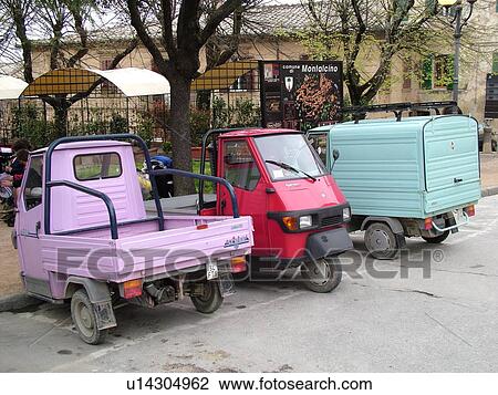Stock Image -  pick-up trucks, Tuscany, Italy, Montalcino, Toscana, Europe, Small pick-up trucks parked along the road in the city of Montalcino.. Fotosearch
