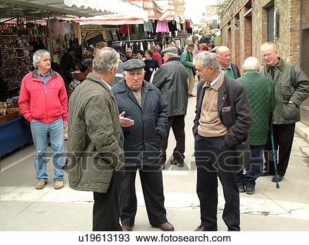 Stock Image -  Tuscany, Italy, Montalcino, Toscana, Europe, Local Italian men talking together on the street in the town of Montalcino.. Fotosearch