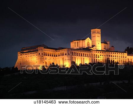 Stock Image -  Assisi, Italy, Umbria, Europe, Basilica di San Francesco (Basilica of St. Francis of Assisi) and the Sacro Convento illuminated at night on the slopes of Monte Subasio in the medieval hill town of Assisi.. Fotosearch