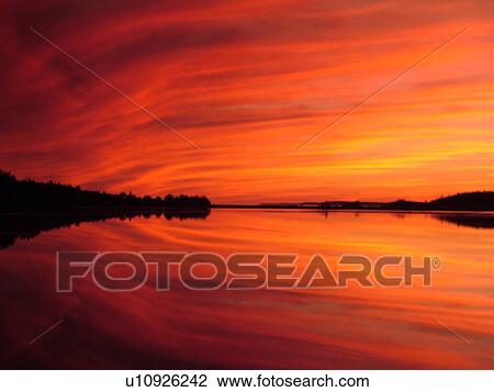 Stock Image -  Canada, New Brunswick, Maces Bay, Bay of Fundy, Colorful reflection at sunrise on the calm waters of the Bay of Fundy at sunset.. Fotosearch