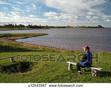 Canada, Prince Edward Island, Gulf of Saint Lawrence, Prince County, Northumberland Strait, woman sitting on bench along coast View Large Photo Image Stock Photo - Canada, Prince Edward Island, Gulf of Saint Lawrence, Prince County, Northumberland Strait, woman sitting on bench along coast. Fotosearch