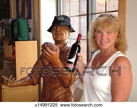 Centerport, NY, New York, Long Island, Duck Walk Vineyards, winery, interior, tasting room, woman holding wine bottle next to statue View Large Photo Image Stock Photography - Centerport, NY, New York, Long Island, Duck Walk Vineyards, winery, interior, tasting room, woman holding wine bottle next to statue. Fotosearch