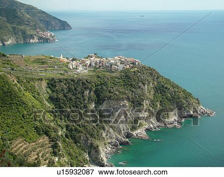 Stock Photo -  Italy, Cinque Terre, Corniglia, Liguria, Riviera di Levante, Ligurian Riviera, Europe, Scenic view of Corniglia, a Cinque Terre village, along the steep rocky coastline of the Ligurian Sea.. Fotosearch