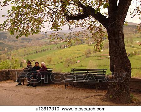 Stock Image -  Italy, Tuscany, Poppi, Toscana, Europe, Elderly Italian people sitting on a bench in the town of Poppi in the Casentino hill region.. Fotosearch