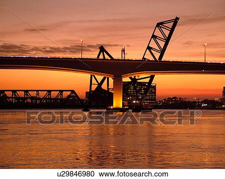 Stock Image -  Jacksonville, FL, Florida, Fuller Warren Bridge & Railroad Acosta Bridge span the St. Johns River at sunset. Fotosearch