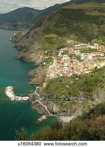 Stock Image -  Liguria, Italy, Cinque Terre, Riomaggiore, Riviera di Levante, Ligurian Riviera, Europe, Scenic view of Riomaggiore, a Cinque Terre village, along the steep rocky coastline of the Ligurian Sea.. Fotosearch