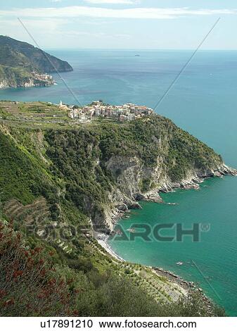 Stock Image -  Liguria, Italy, Cinque Terre, Corniglia, Riviera di Levante, Ligurian Riviera, Europe, Scenic view of Corniglia, a Cinque Terre village, along the steep rocky coastline of the Ligurian Sea.. Fotosearch
