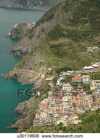 Stock Photograph -  Liguria, Italy, Cinque Terre, Riomaggiore, Riviera di Levante, Ligurian Riviera, Europe, Scenic view of Riomaggiore, a Cinque Terre village, along the steep rocky coastline of the Ligurian Sea.. Fotosearch
