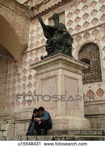 Perugia, Umbria, Italy, Europe, A couple sits on the steps below a religious statue outside the Cathedral of San Lorenzo in the medieval town of Perugia. View Large Photo Image Stock Image - Perugia, Umbria, Italy, Europe, A couple sits on the steps below a religious statue outside the Cathedral of San Lorenzo in the medieval town of Perugia.. Fotosearch