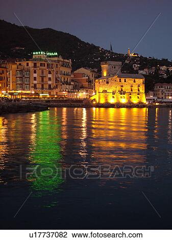 Stock Image -  Rapallo, Riviera di Levante, Liguria, Italy, Ligurian Riviera, Europe, Hotel Italia and the Castle at night on the Gulf of Tigullio (Gulfo di Tigullo) in the resort town of Rapallo along the Ligurian Sea on the Ligurian Riviera.. Fotosearch