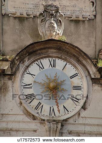 Stock Image -  Spoleto, Italy, Umbria, Europe, Clock on the front of an old building in the Piazza del Mercato in the medieval city of Spoleto.. Fotosearch