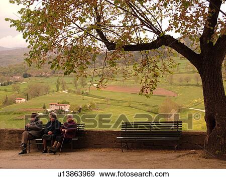 Stock Photo -  Tuscany, Italy, Poppi, Toscana, Europe, Elderly Italian people sitting on a bench in the town of Poppi in the Casentino hill region.. Fotosearch