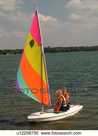 Stock Image -  Alexandria, MN, Minnesota, Maple Lake, couple sailing, sunfish, sailboat. Fotosearch
