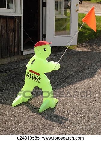 Stock Photography -  creative slow down sign, small green figure with orange flag. Fotosearch