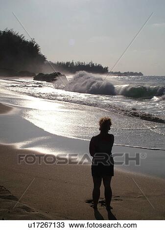 Stock Image -  Hanalei, Princeville, Kauai, HI, Hawaii, North Shore, Lumahai Beach, woman taking video of waves. Fotosearch
