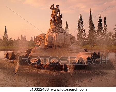 Stock Photograph -  Hanalei, Princeville, Kauai, HI, Hawaii, North Shore, Fountain and statue of Neptune at the entrance of a resort complex, sunset. Fotosearch