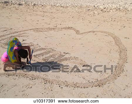 Stock Image -  Kailu, Oahu, HI, Hawaii, Windward Coast, Kailu beach, young girl drawing in sand. Fotosearch
