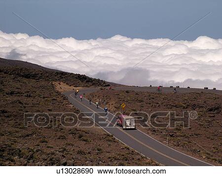 Stock Image -  Maui, HI, Hawaii, Haleakala National Park, biking down the volcano, above the clouds. Fotosearch