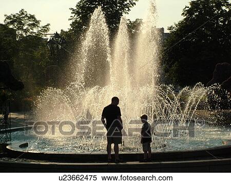 Stock Photography -  Montreal, Canada, QC, Quebec, Old Port, Old Montreal, Place Jacques Cartier, Place Vauquelin, fountain, silhouette of father and son. Fotosearch