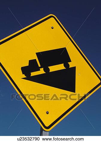 Stock Image -  road sign, Hill, Steep Grade Ahead, trucks use low gear sign against a blue sky, warning sign. Fotosearch