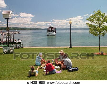 Stock Image -  Skaneateles, NY, New York, Finger Lakes Region, Skaneateles Lake, Mid Lakes Navigation Company, excursion, sightseeing tour boat, family resting at the waterfront park. Fotosearch