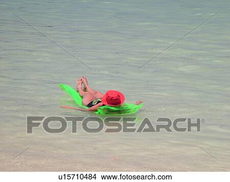Picture -  Waikiki, Honolulu, Oahu, HI, Hawaii, Kuhio Beach Park, woman on green float in water, red hat. Fotosearch