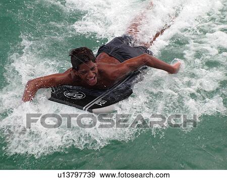 Stock Photo -  Waikiki, Honolulu, Oahu, HI, Hawaii, Queen's Surf Beach, boogie boarding. Fotosearch