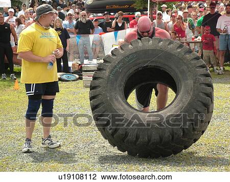 Stock Image -  Windsor, VT, Vermont, Harpoon Championships of New England Barbecue, Strong Man Competition, man lift and pushing huge heavy rubber tire. Fotosearch