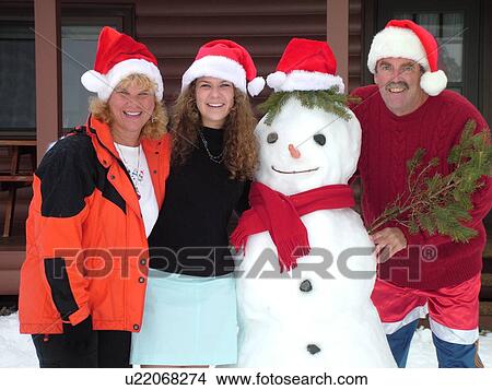 Picture -  Alexandria, MN, Minnesota, Maple Lake, Family wearing red Santa hats posing for Christmas picture with a snowman, humor, snow, winter. Fotosearch