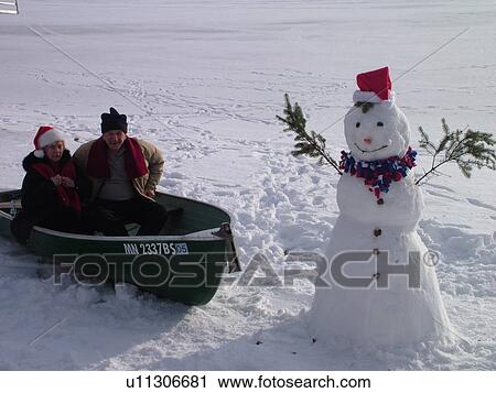 Alexandria, MN, Minnesota, Maple Lake, Senior couple (husband, wife) wearing red Santa hats sitting in a green rowboat in the snow, snowman, humor, frozen lake, winter View Large Photo Image Stock Image - Alexandria, MN, Minnesota, Maple Lake, Senior couple (husband, wife) wearing red Santa hats sitting in a green rowboat in the snow, snowman, humor, frozen lake, winter. Fotosearch
