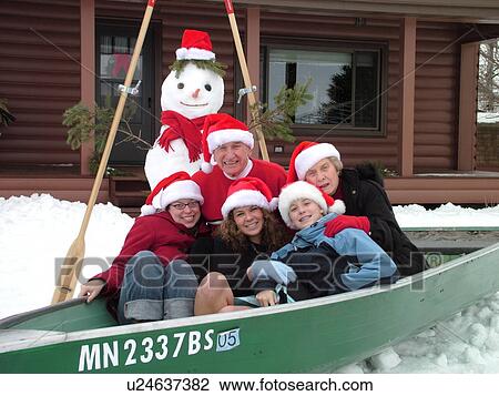 Stock Image -  Alexandria, MN, Minnesota, Maple Lake, Grandparents and granddaughters wearing red Santa hats posing for Christmas picture sitting in a green rowboat in the snow, humor, winter, snowman. Fotosearch