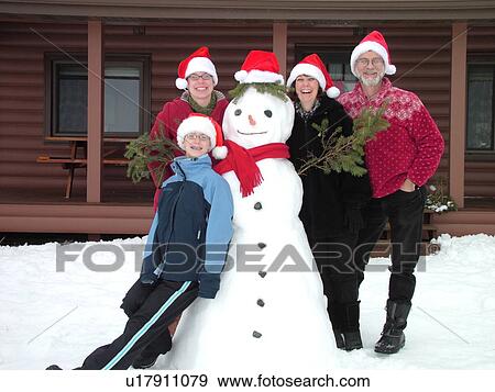 Stock Photo -  Alexandria, MN, Minnesota, Maple Lake, Family wearing red Santa hats posing for Christmas picture with a snowman, humor, snow, winter. Fotosearch