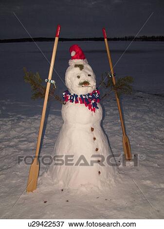 Alexandria, MN, Minnesota, Maple Lake, snowman wearing a red Santa hat holding oars, snow, winter, evening View Large Photo Image Stock Photo - Alexandria, MN, Minnesota, Maple Lake, snowman wearing a red Santa hat holding oars, snow, winter, evening. Fotosearch