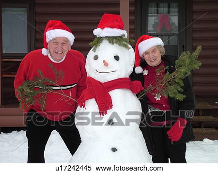 Alexandria, MN, Minnesota, Maple Lake, Husband and wife wearing Santa hats posing for Christmas picture with a snowman, humor, snow, winter, senior couple View Large Photo Image Stock Photography - Alexandria, MN, Minnesota, Maple Lake, Husband and wife wearing Santa hats posing for Christmas picture with a snowman, humor, snow, winter, senior couple. Fotosearch