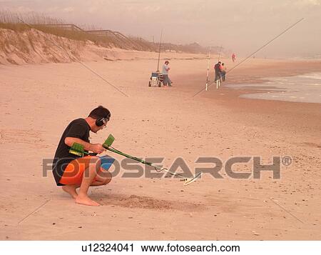 Stock Image -  Amelia Island, FL, Florida, Fernandina Beach, Atlantic Ocean, man on beach with metal detector. Fotosearch