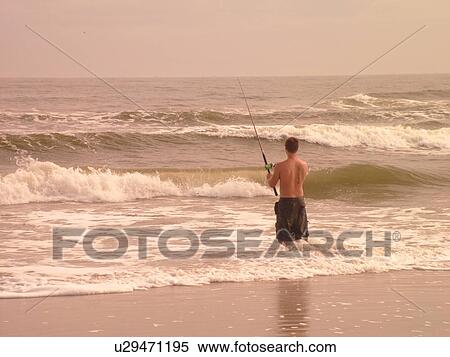 Stock Photography -  Amelia Island, FL, Florida, Fernandina Beach, Atlantic Ocean, young man surf fishing on beach. Fotosearch