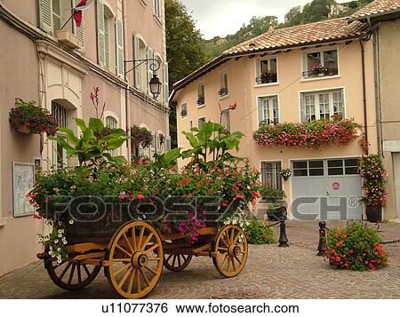 Stock Photograph -  France, Beaujeu, Rhone-Alpes, Europe, Heart of Beaujolais, flowers decorate the village, wagon, window boxes. Fotosearch