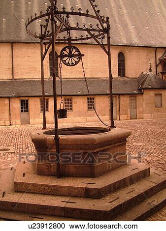 Stock Image -  France, Beaune, Burgundy, Cote de Beaune, Cote d'Or, Europe, Burgundy Wine Region, downtown, Hotel-Dieu, Cour d'Honneur, stone well. Fotosearch