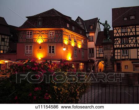 Stock Photograph -  France, Europe, Alsace, Colmar, Haut-Rhin, L'Alsace Wine Region, Route du Vin, downtown, evening, half-timbered buildings, fountain. Fotosearch