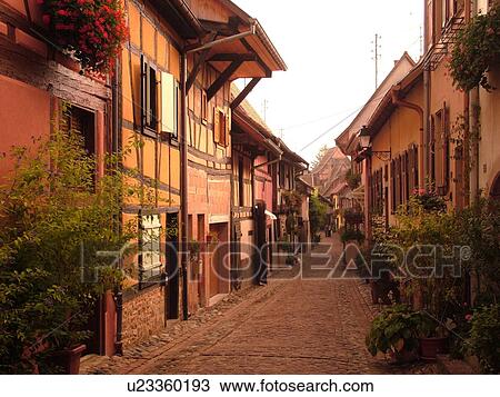Stock Image -  France, Europe, Alsace, Eguisheim, Haut-Rhin, L'Alsace Wine Region, Route du Vin, picturesque village, half-timbered buildings, narrow cobblestone pedestrian street. Fotosearch