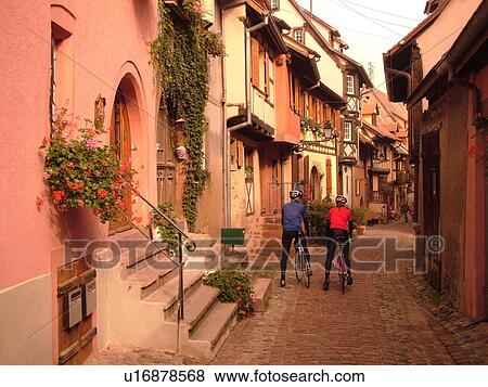 France, Europe, Alsace, Eguisheim, Haut-Rhin, L'Alsace Wine Region, Route du Vin, picturesque village, half-timbered buildings, bikers bike down narrow cobblestone pedestrian street View Large Photo Image Stock Photo - France, Europe, Alsace, Eguisheim, Haut-Rhin, L'Alsace Wine Region, Route du Vin, picturesque village, half-timbered buildings, bikers bike down narrow cobblestone pedestrian street. Fotosearch