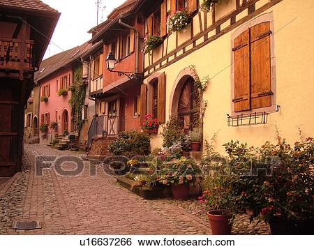 Stock Photograph -  France, Europe, Alsace, Eguisheim, Haut-Rhin, L'Alsace Wine Region, Route du Vin, picturesque village, half-timbered buildings, narrow cobblestone pedestrian street. Fotosearch