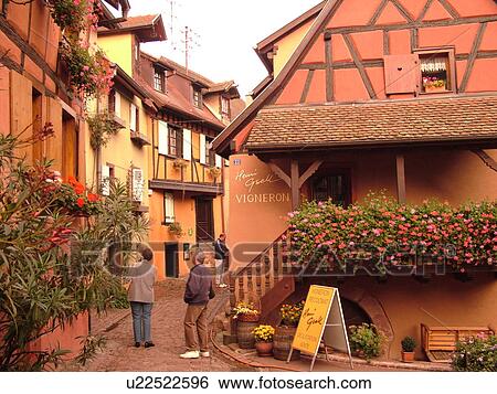 Stock Photograph -  France, Europe, Alsace, Eguisheim, Haut-Rhin, L'Alsace Wine Region, Route du Vin, picturesque village decorated with flowers, half-timbered buildings, narrow cobblestone pedestrian street. Fotosearch