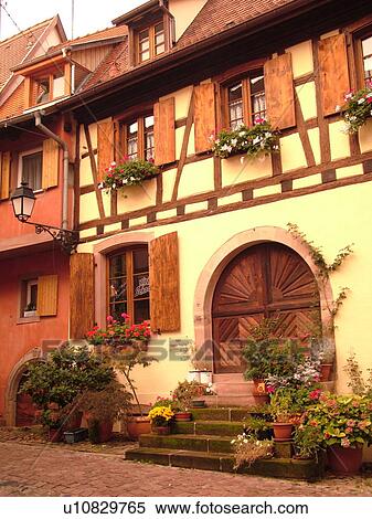 Stock Photography -  France, Europe, Alsace, Eguisheim, Haut-Rhin, L'Alsace Wine Region, Route du Vin, picturesque village, half-timbered buildings, wooden arched door, wooden shutters. Fotosearch