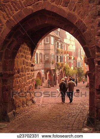 Stock Image -  France, Europe, Alsace, Riquewihr, Haut-Rhin, L'Alsace Wine Region, Route du Vin, downtown, archway, cobblestone pedestrian street. Fotosearch