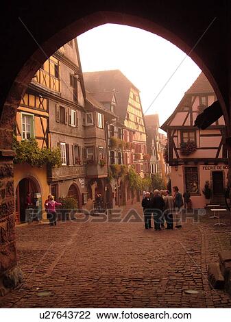 Stock Image -  France, Europe, Alsace, Riquewihr, Haut-Rhin, L'Alsace Wine Region, Route du Vin, downtown, archway, cobblestone pedestrian street, half-timbered buildings. Fotosearch