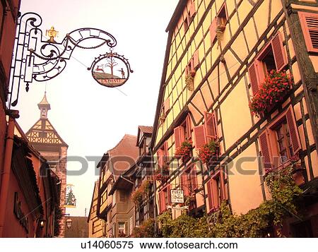 Stock Photography -  France, Europe, Alsace, Riquewihr, Haut-Rhin, L'Alsace Wine Region, Route du Vin, downtown, half-timbered buildings, hanging store sign. Fotosearch