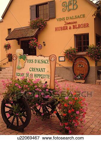 Stock Photo -  France, Europe, Alsace, St-Hippolyte, Haut-Rhin, L'Alsace Wine Region, Route du Vin, village, winery, wooden cart decorated with flowers. Fotosearch
